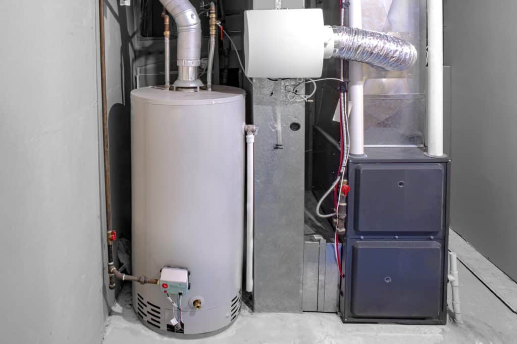 A gas water heater and furnace with connected ductwork and piping installed in a residential utility area.